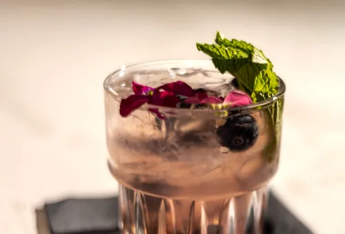 Signature cocktail with mint, rose petals and blueberry at Bellini