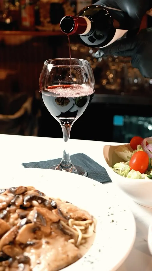 Red wine poured beside chicken marsala and a house salad