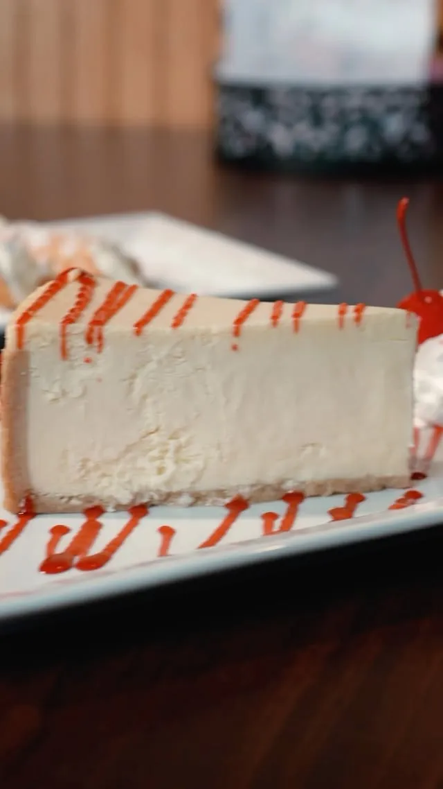 A slice of cheesecake with strawberry sauce and whipped cream