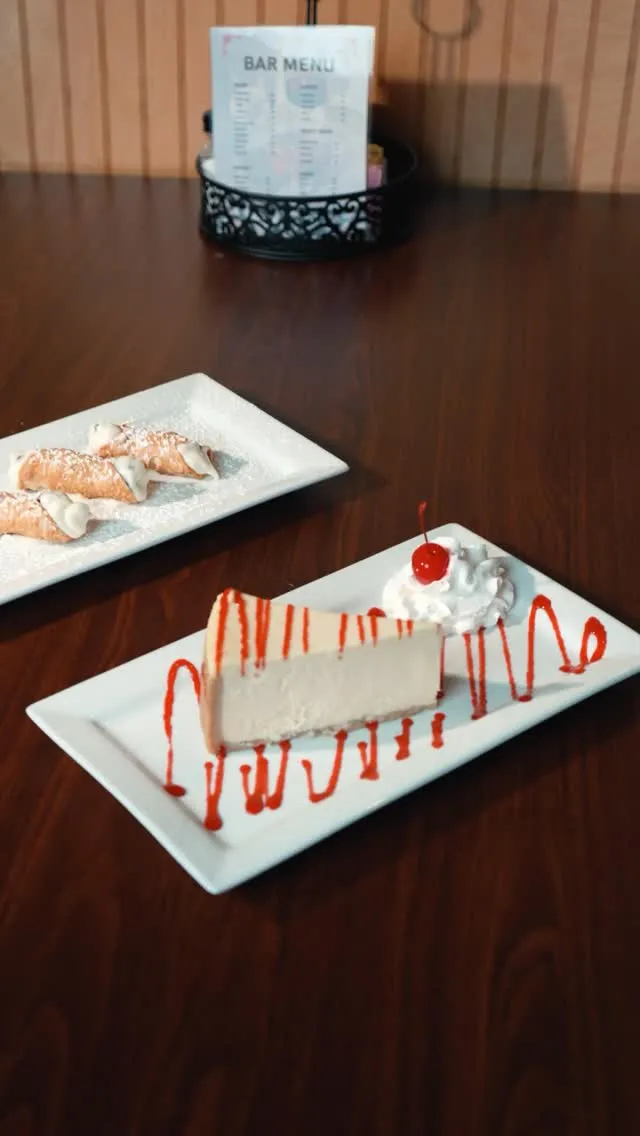 Cheesecake with strawberry sauce and cannoli on the table